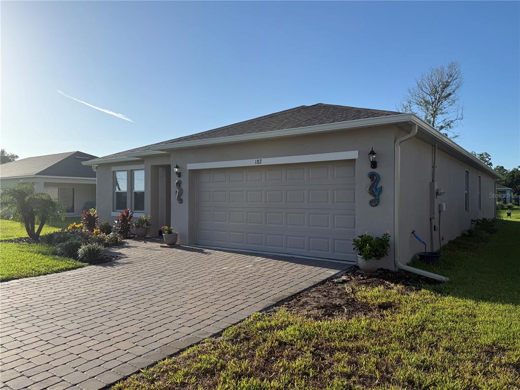 A single-story house with a beige exterior, a two-car garage, and a paved driveway — 182 JONES FISH CAMP ROAD, EDGEWATER, FL