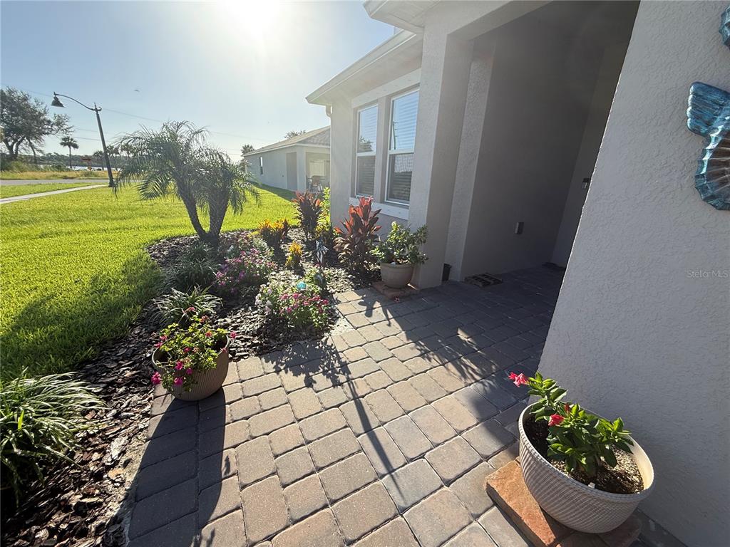 A paved walkway leads to the front entrance of a house with landscaped garden beds — 182 JONES FISH CAMP ROAD, EDGEWATER, FL