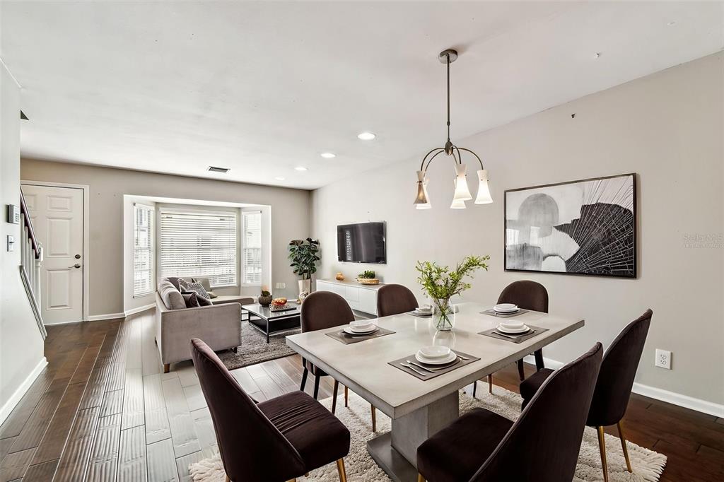 A dining area with a modern table and chairs sits adjacent to a living room — 609 S GLEN AVENUE UNIT E, TAMPA, FL