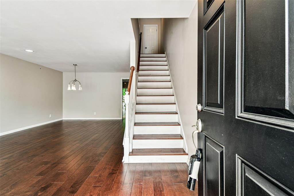 A view from an open front door shows a living area with hardwood floors and stairs — 609 S GLEN AVENUE UNIT E, TAMPA, FL