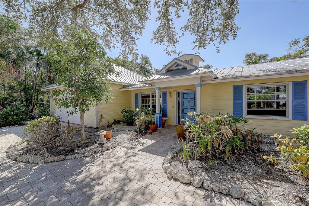 A yellow house with a metal roof, blue shutters, and a paved stone walkway — 226 OGDEN STREET, SARASOTA, FL