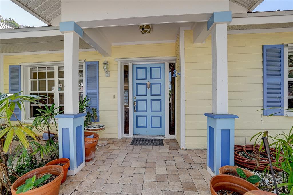 A light yellow house exterior features a blue front door, blue shutters, and stone pavers — 226 OGDEN STREET, SARASOTA, FL