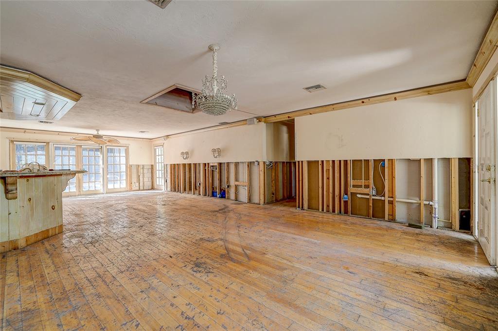 An unfinished room with exposed wall studs, wood flooring, a kitchen island, and a chandelier — 226 OGDEN STREET, SARASOTA, FL