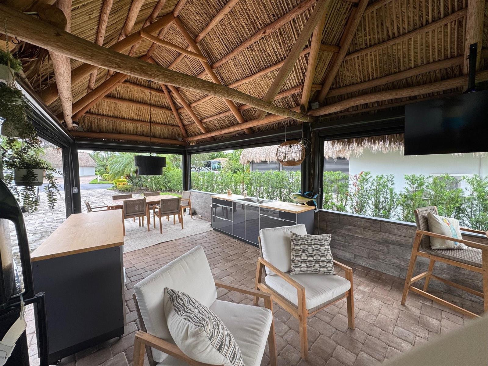 An open-air patio with a thatched roof, outdoor kitchen, dining area, and lounge seating — 373 Sundial Circle # 373, Margate FL 33068, MARGATE, FL