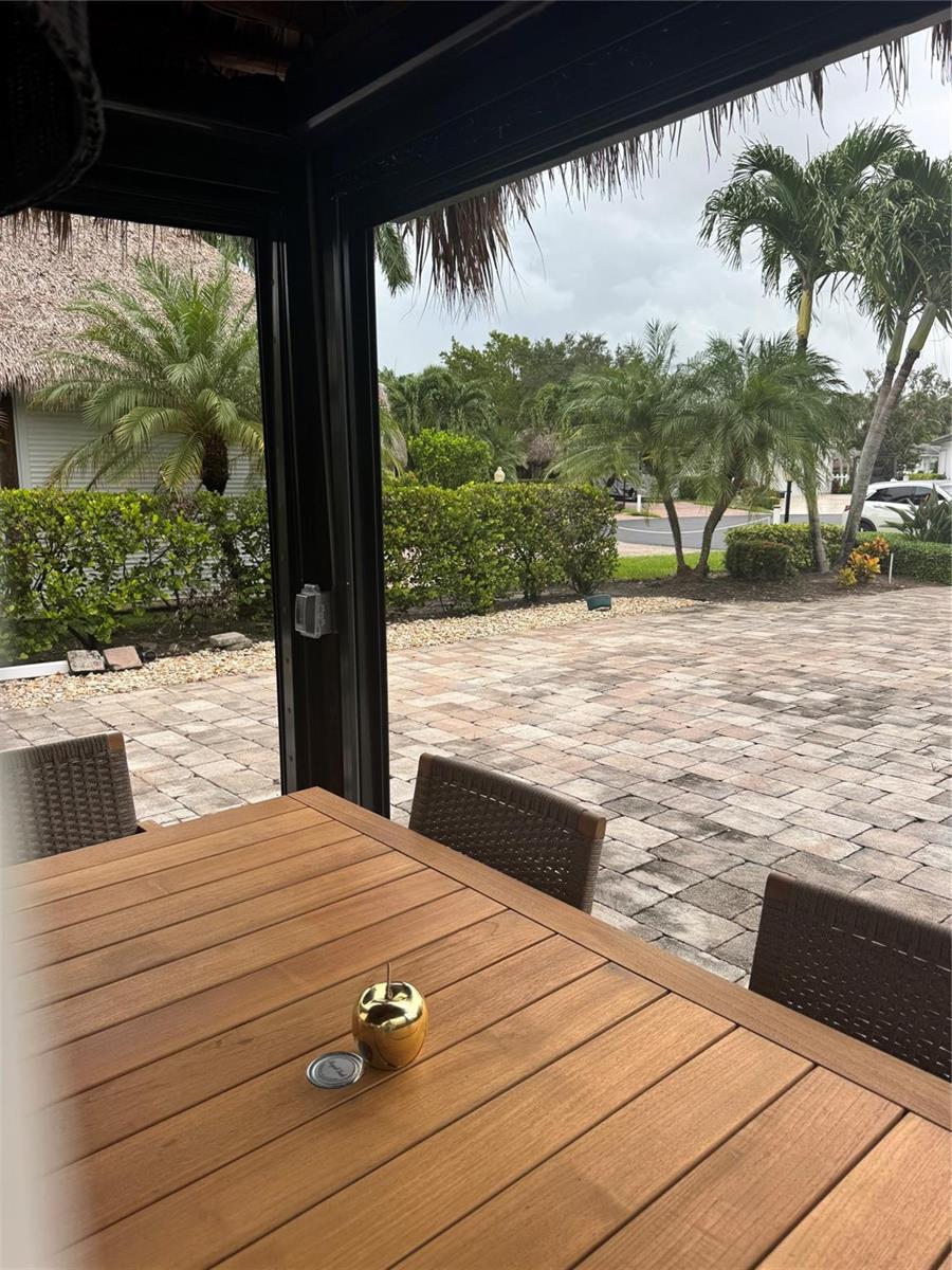 A wooden table sits on a covered patio overlooking a paved driveway and palm trees — 373 Sundial Circle # 373, Margate FL 33068, MARGATE, FL