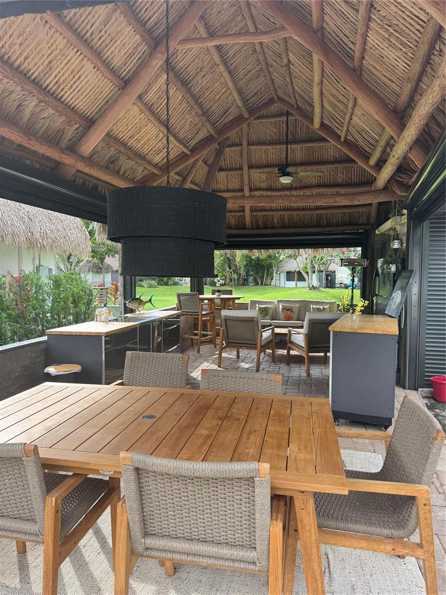 A covered outdoor patio features a thatched roof, dining area, kitchen island, and lounge seating — 373 Sundial Circle # 373, Margate FL 33068, MARGATE, FL