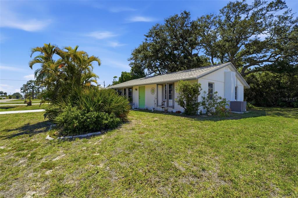 A single-story house with a light-colored exterior, a bright green door, and large shade trees — 1240 S VENICE BOULEVARD, VENICE, FL