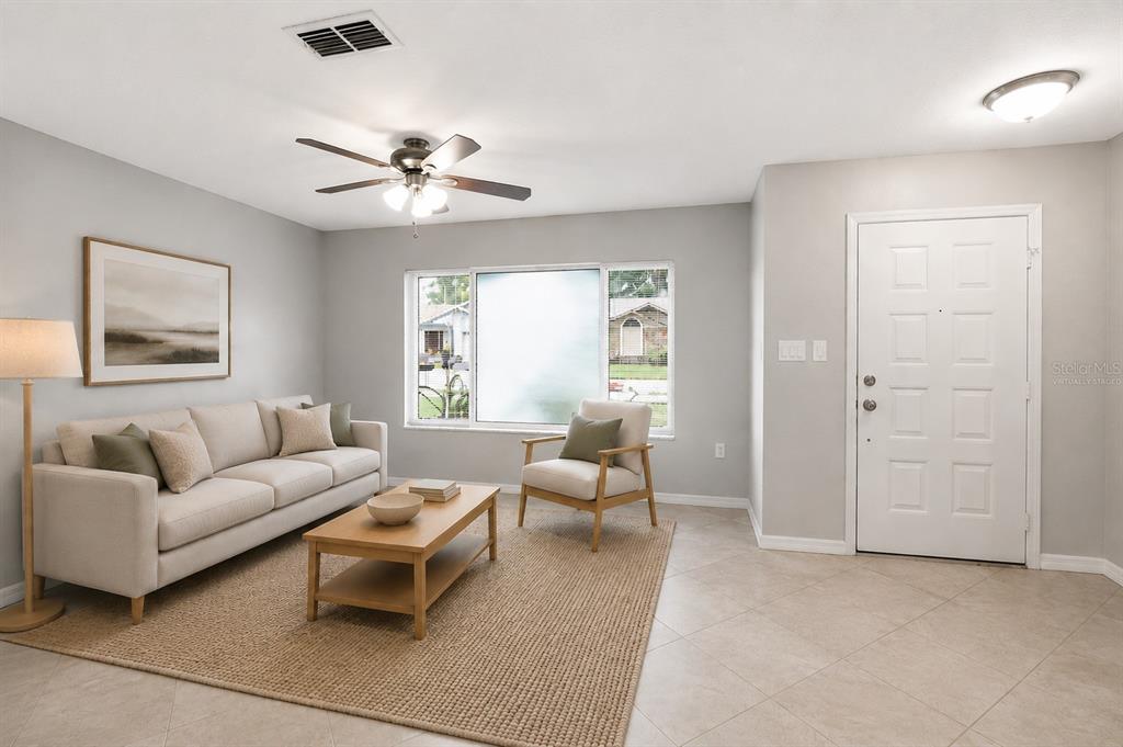 A living room with a beige sofa, armchair, coffee table, and a white front door — 9504 VIA SEGOVIA, NEW PORT RICHEY, FL
