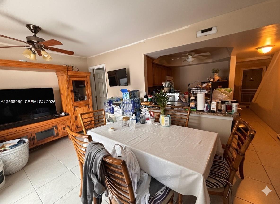 A dining area features a table with chairs, a television console, and an open kitchen — 1415 NW 80th Ave # D, Margate FL 33063, MARGATE, FL