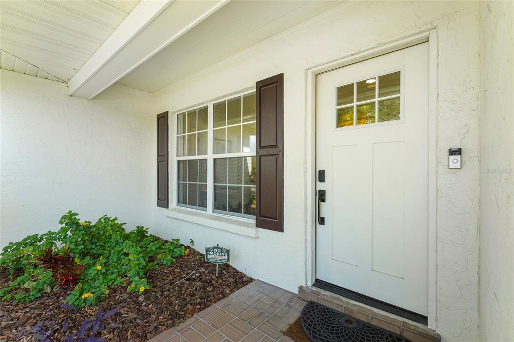 A white front door with a window sits beside a window with dark shutters — 7746 WESTMORELAND DRIVE, SARASOTA, FL