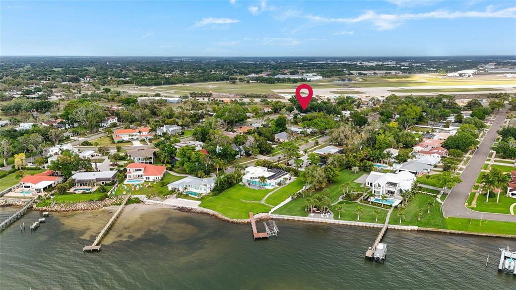 An aerial view shows waterfront houses with private docks along a bay near an airport — 7746 WESTMORELAND DRIVE, SARASOTA, FL