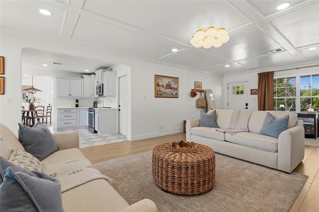 A living room with a coffered ceiling, light wood floors, and an open kitchen area — 7746 WESTMORELAND DRIVE, SARASOTA, FL