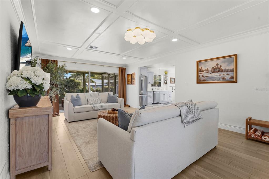A living room with light wood floors, a coffered ceiling, and two sofas — 7746 WESTMORELAND DRIVE, SARASOTA, FL
