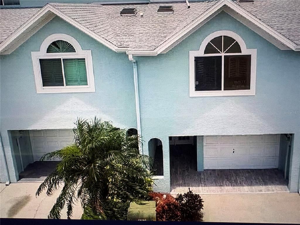 An exterior view of a two-story light blue townhouse with two garages and arched windows — 629 GARLAND CIRCLE, INDIAN ROCKS BEACH, FL