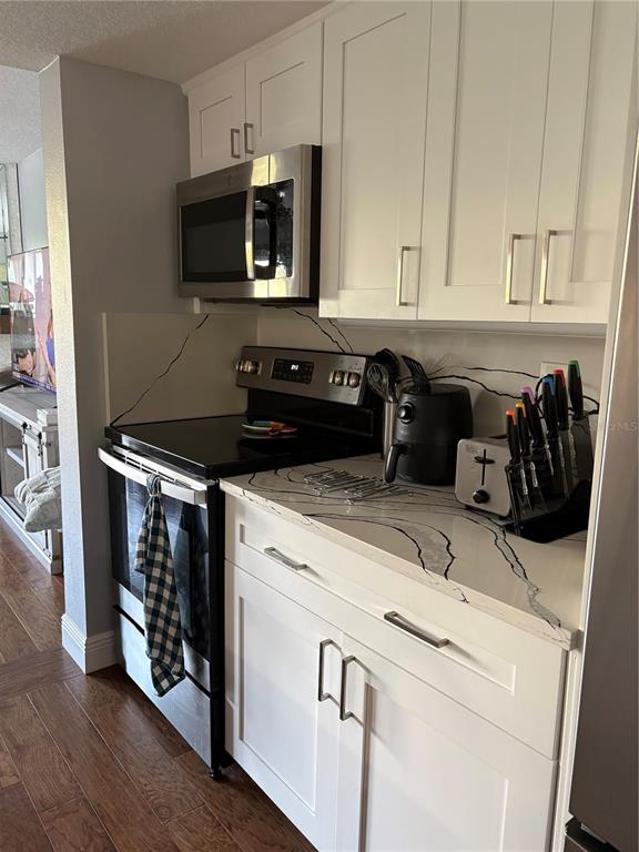 A kitchen features white cabinets, stainless steel appliances, and white countertops with black veining — 629 GARLAND CIRCLE, INDIAN ROCKS BEACH, FL