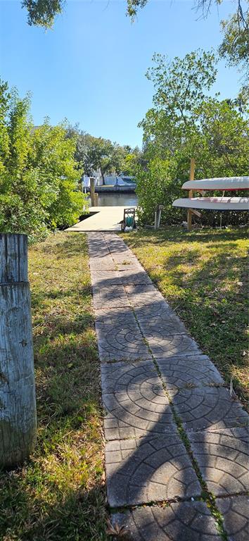 A paved walkway leads through a grassy yard toward a wooden dock on the water — TENNESSEE AVENUE, CRYSTAL BEACH, FL