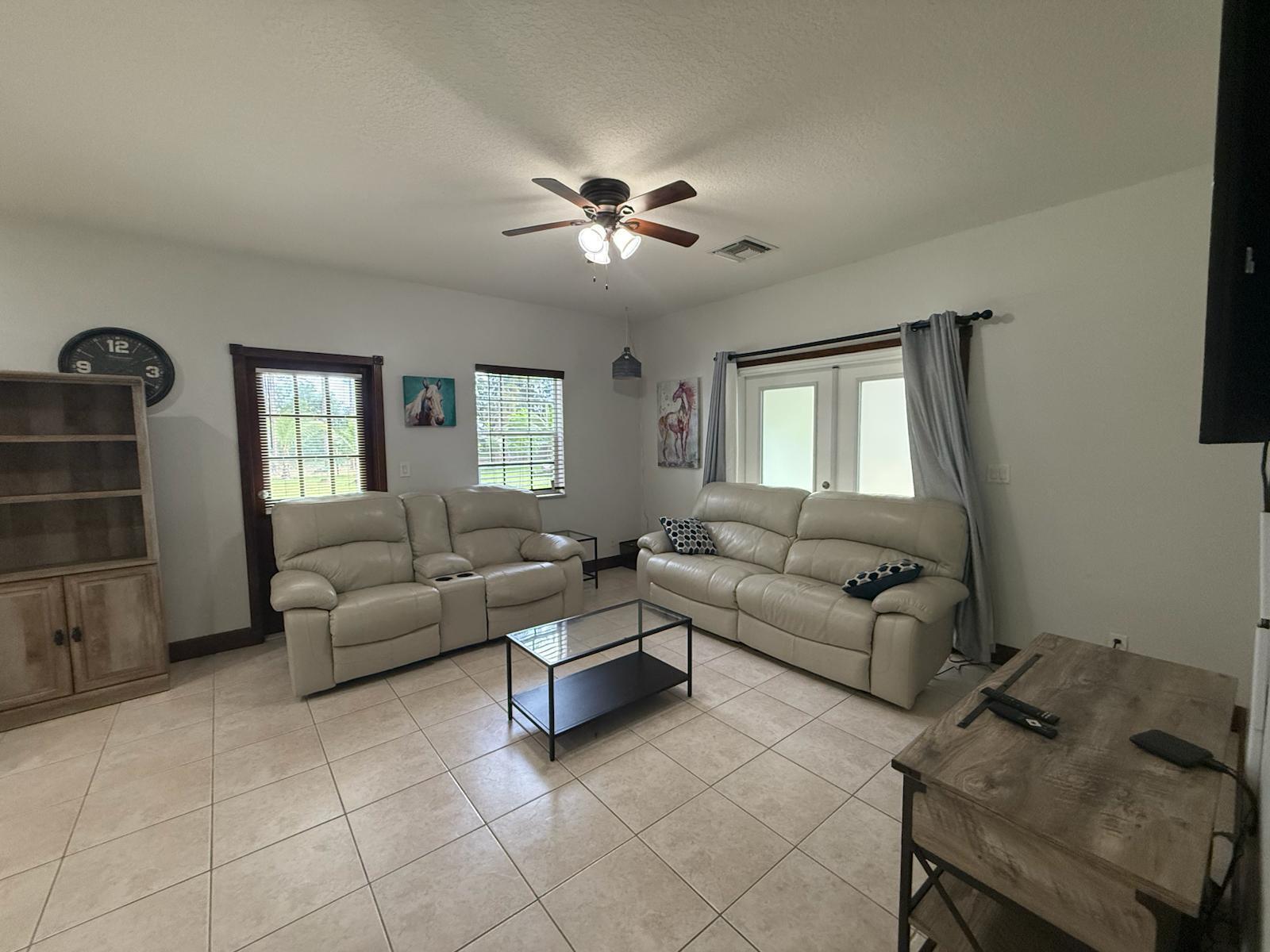 A living room features light tile flooring, two leather sofas, and a glass coffee table — 15831 N 44th St Street N, FL 33470, FL