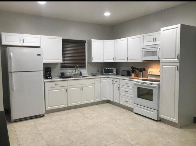 A kitchen with white cabinets, white appliances, light tile flooring, and a window with blinds — 15831 N 44th St Street N, FL 33470, FL