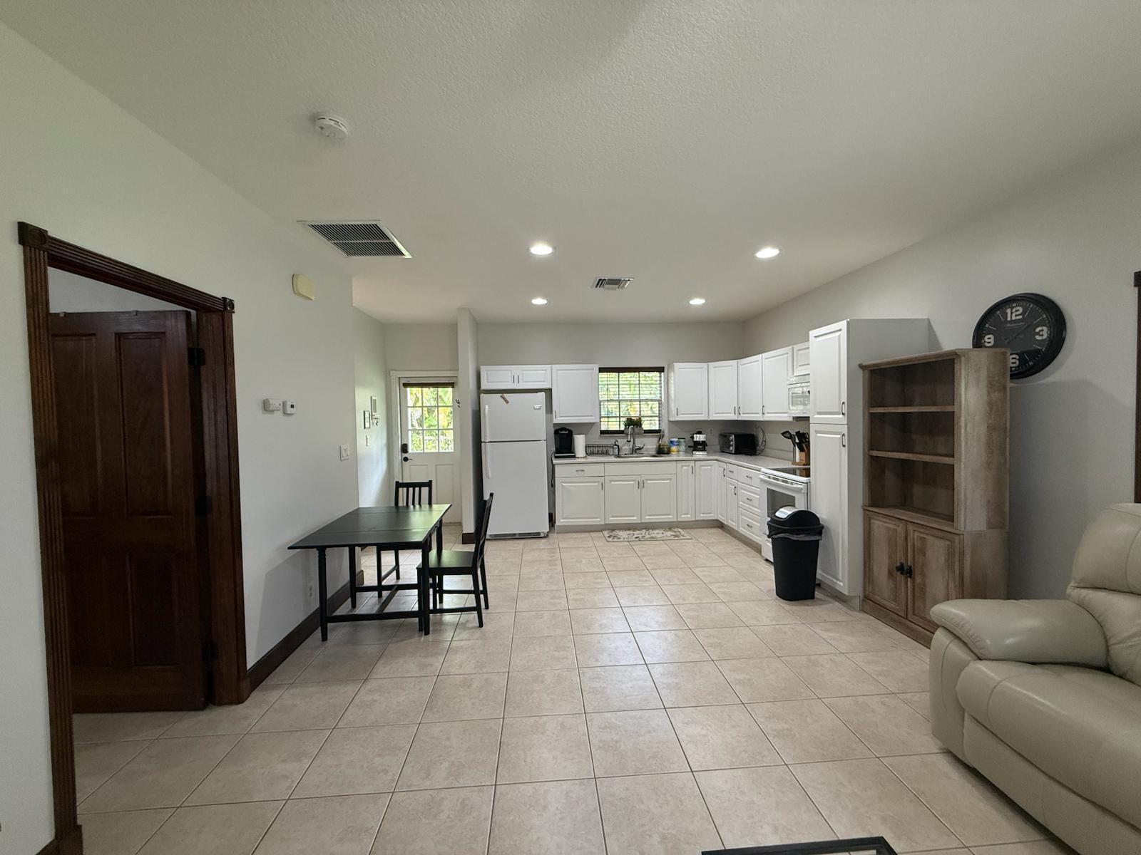 A kitchen with white cabinets, tile flooring, and a dining table near a back door — 15831 N 44th St Street N, FL 33470, FL