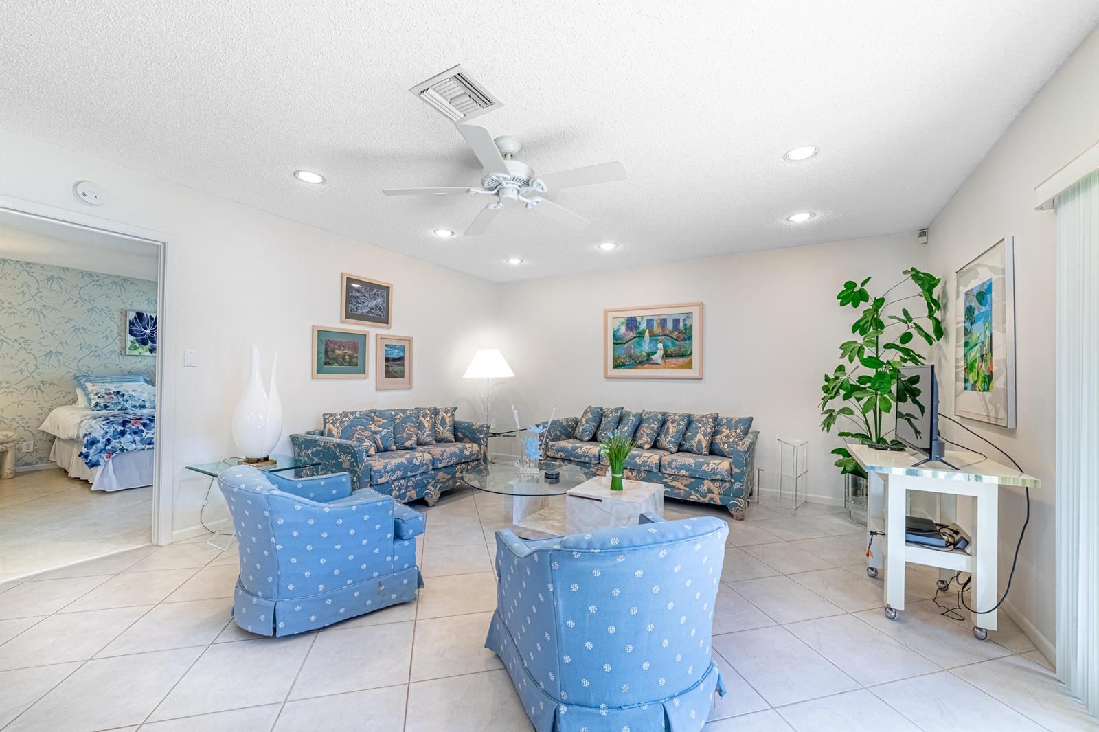 A living room features blue patterned sofas and armchairs, tile flooring, and a ceiling fan — 797 NW 32nd Avenue, Delray Beach FL 33445, DELRAY BEACH, FL