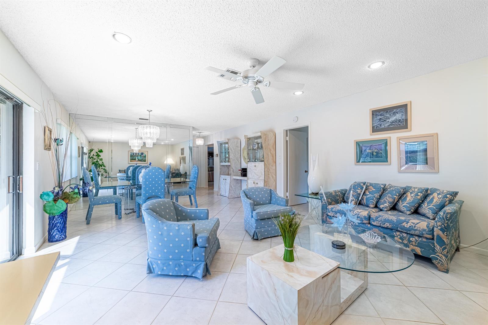 A living and dining room with blue patterned furniture, tile floors, and a mirrored wall — 797 NW 32nd Avenue, Delray Beach FL 33445, DELRAY BEACH, FL