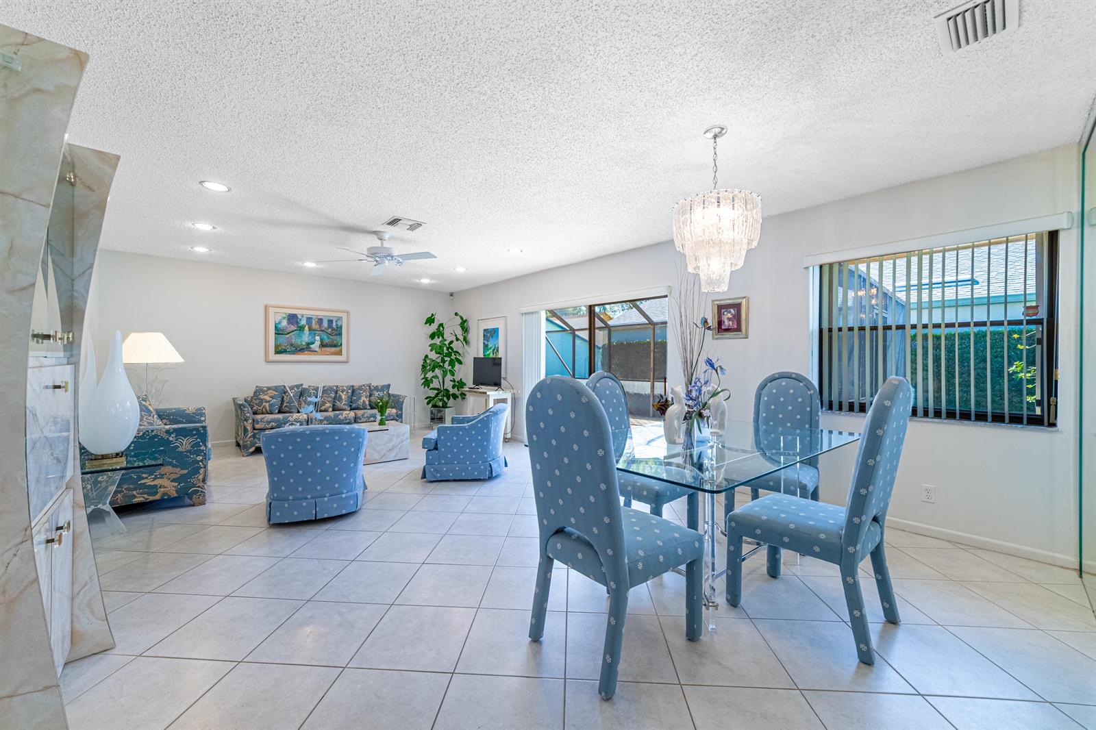 A bright, open-concept living and dining area features blue patterned furniture and tile flooring — 797 NW 32nd Avenue, Delray Beach FL 33445, DELRAY BEACH, FL