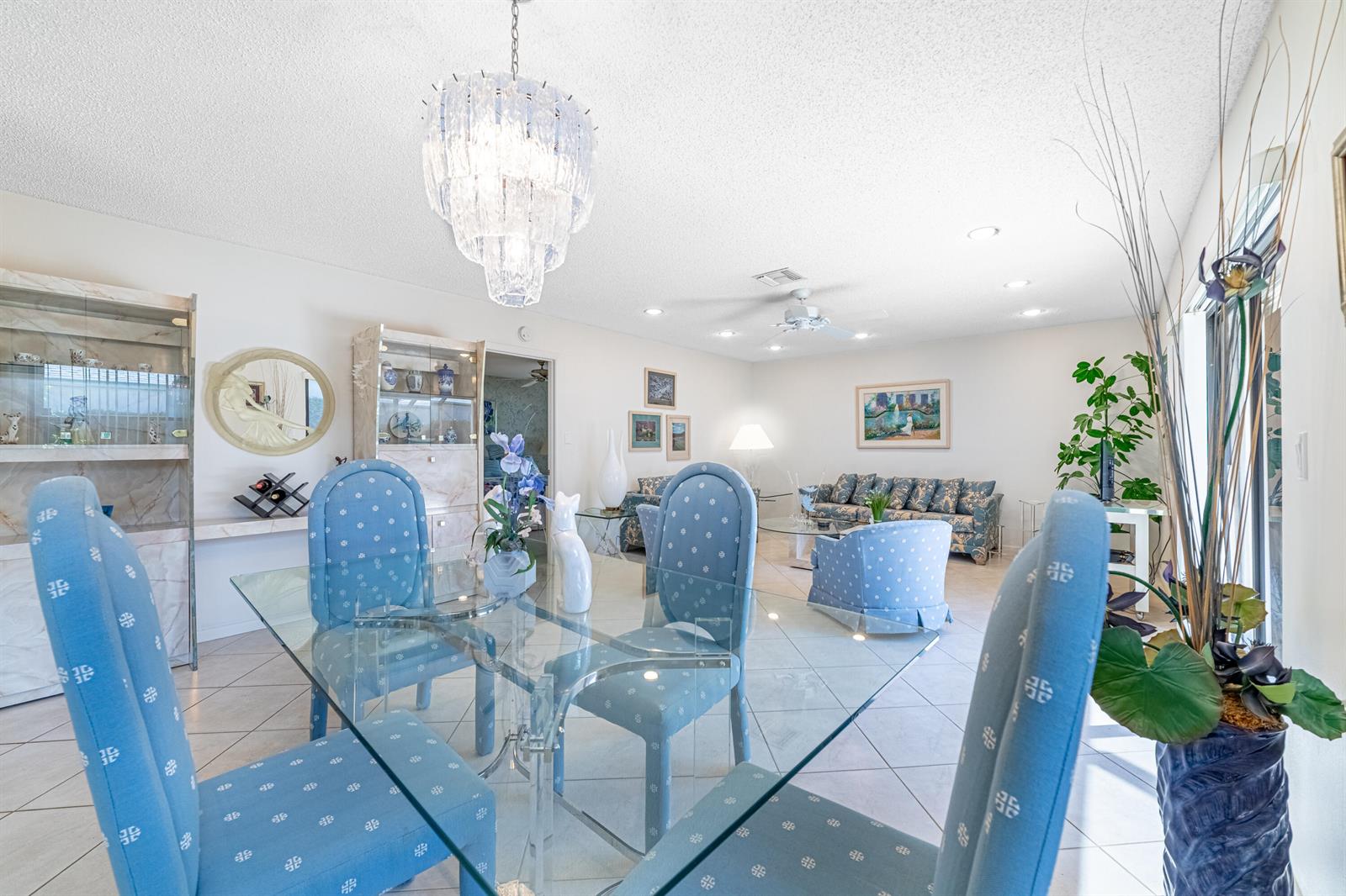 A dining area with a glass table and blue patterned chairs opens into a living room — 797 NW 32nd Avenue, Delray Beach FL 33445, DELRAY BEACH, FL