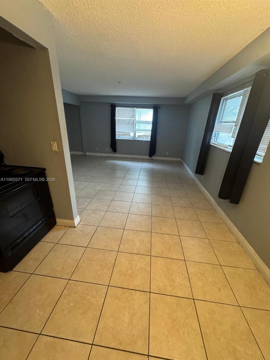 A tiled living area features gray walls, dark curtains, and a view into the kitchen — 4251 NW 5th St # 106, Plantation FL 33317, PLANTATION, FL
