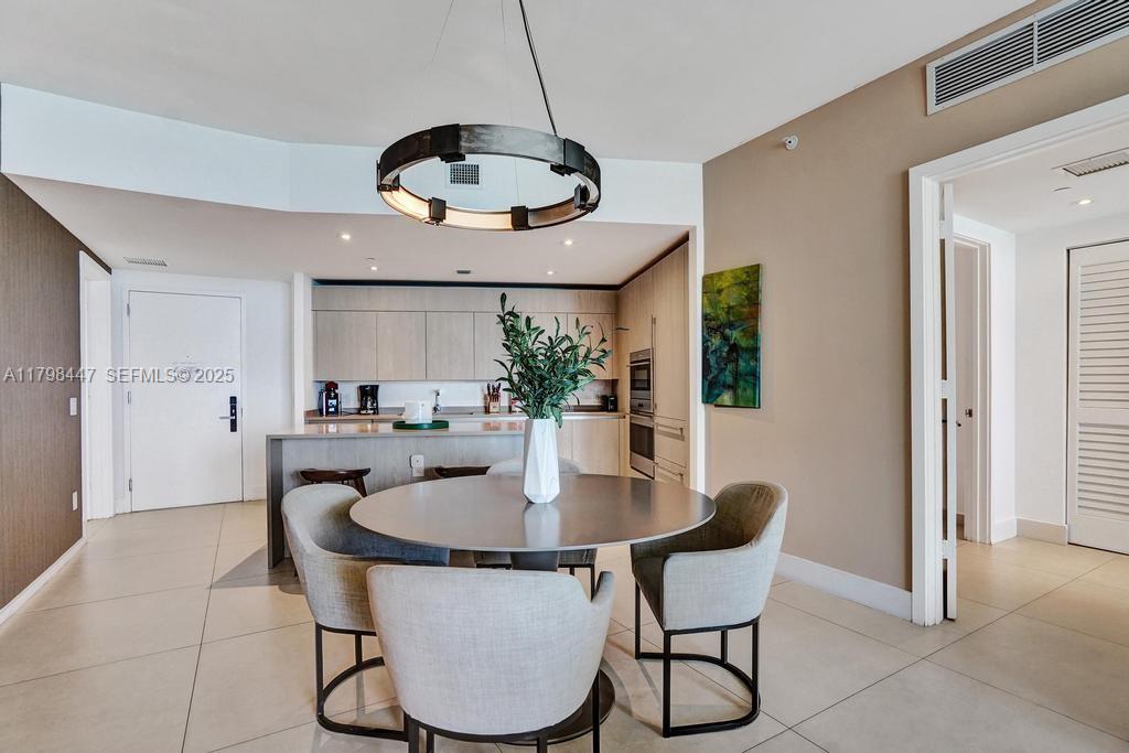 A dining area with a round table and chairs sits in front of a modern kitchen — 4111 S Ocean Dr # 2803, Hollywood FL 33019, HOLLYWOOD, FL