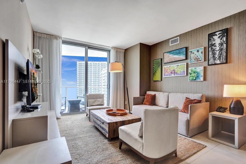 A living room features a sofa, armchairs, a wooden coffee table, and a balcony view — 4111 S Ocean Dr # 2803, Hollywood FL 33019, HOLLYWOOD, FL