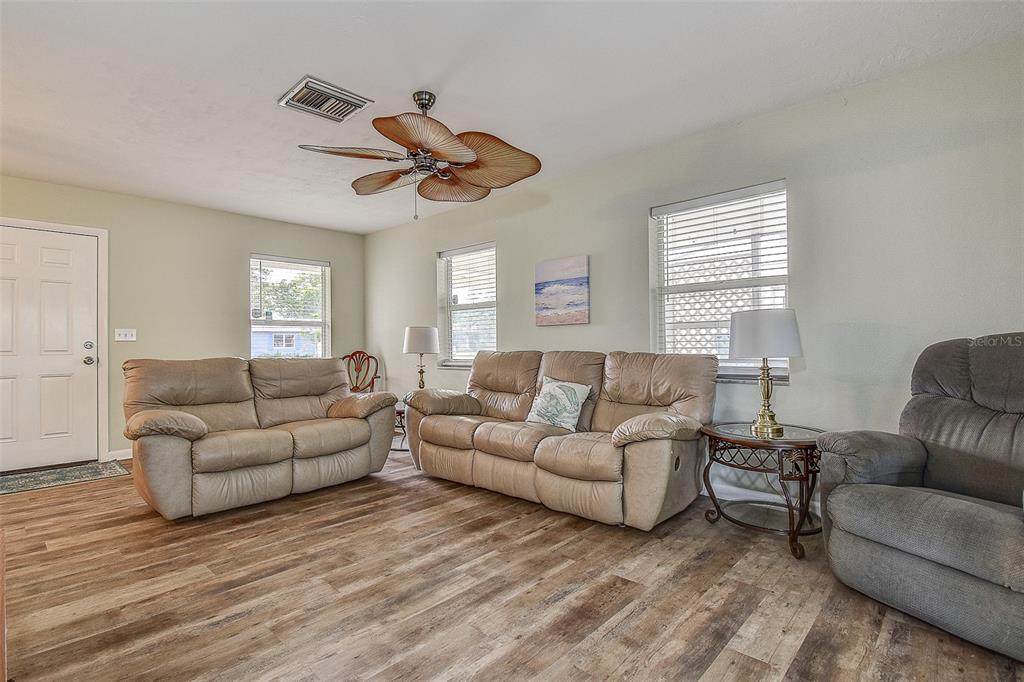A living room features light-colored walls, wood-look flooring, a ceiling fan, and leather furniture — 6237 DALTON STREET, SPRING HILL, FL