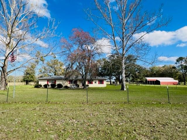 A single-story house with red shutters sits on a grassy lot near a red barn — 10 SW 50TH AVENUE, BELL, FL