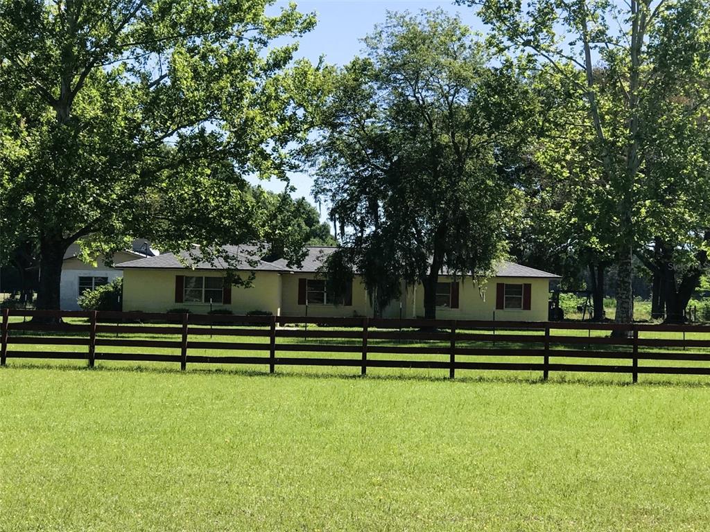 A single-story house with a brown roof sits behind a wooden fence in a yard — 10 SW 50TH AVENUE, BELL, FL