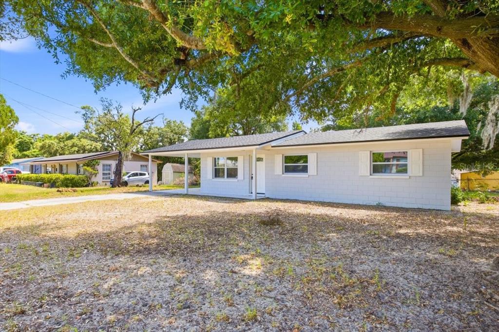 A single-story white concrete block house with a carport and a concrete driveway — 827 EVERETT STREET, LAKE ALFRED, FL