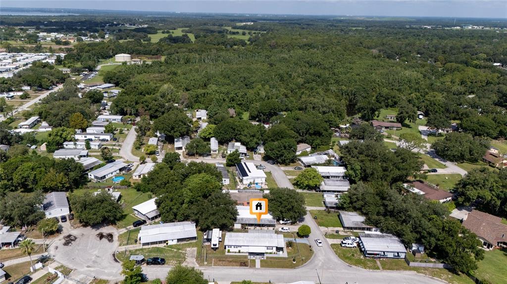 An aerial view shows a residential neighborhood with a highlighted house surrounded by trees — 24 FLAMINGO BOULEVARD, WINTER HAVEN, FL