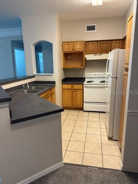 A kitchen features light wood cabinets, a white stove, a refrigerator, and tiled flooring — 3250 CORONA VILLAGE WAY UNIT 108, ORLANDO, FL