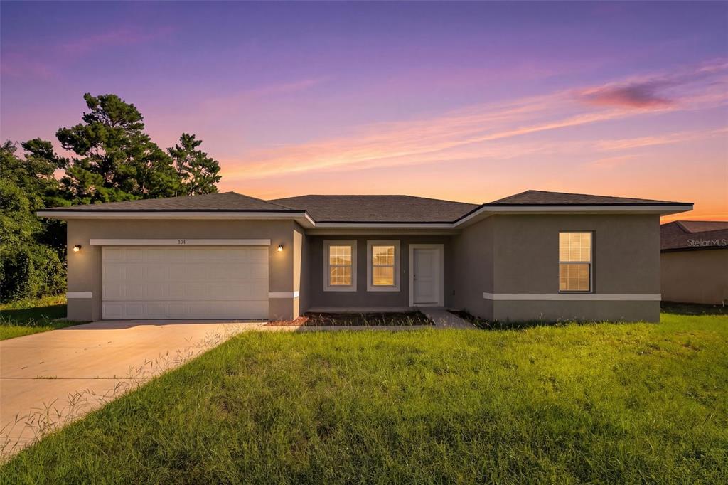 A single-story house with a two-car garage and a concrete driveway at sunset — 304 BEGONIA COURT, POINCIANA, FL