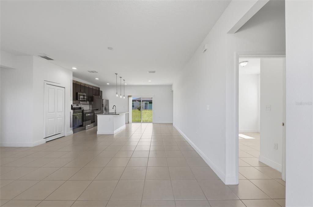 An open-concept kitchen and living area with tile flooring and a sliding glass door — 304 BEGONIA COURT, POINCIANA, FL