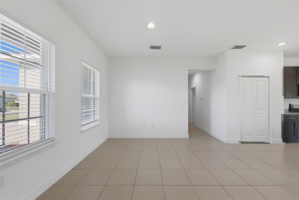 An empty room with white walls, tile flooring, two windows, and a closed white door — 304 BEGONIA COURT, POINCIANA, FL
