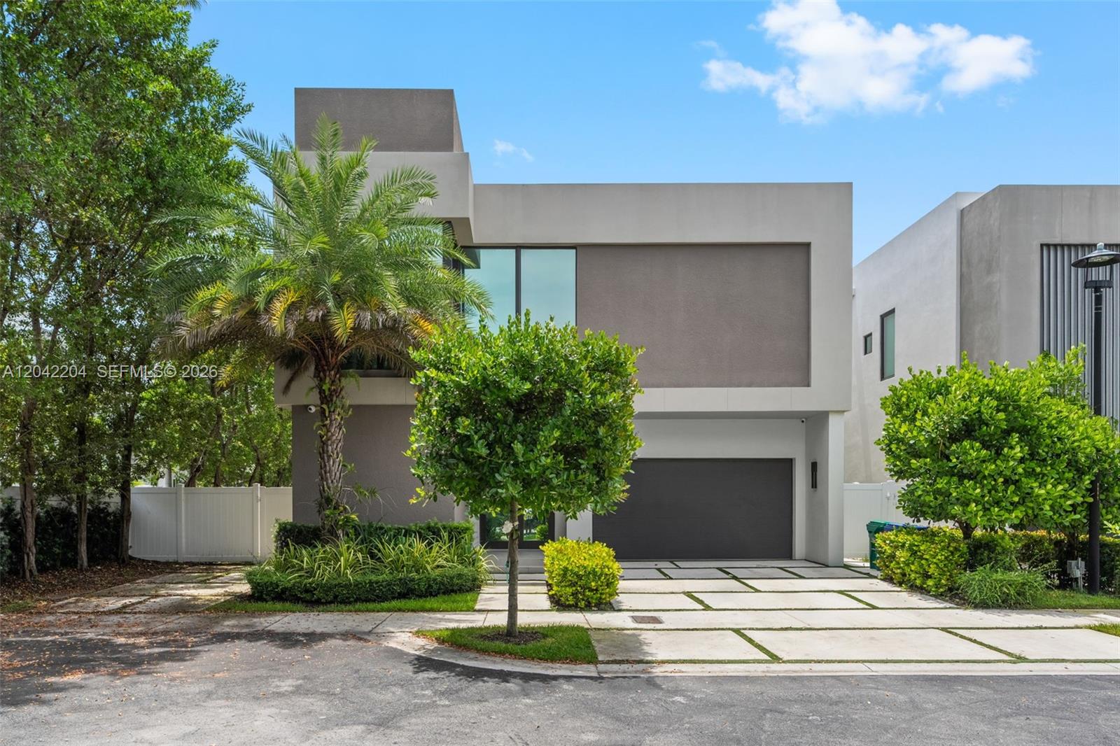 A modern two-story house features a gray facade, a garage, and a palm tree — 6814 NW 104th Ct, Doral FL 33178, DORAL, FL