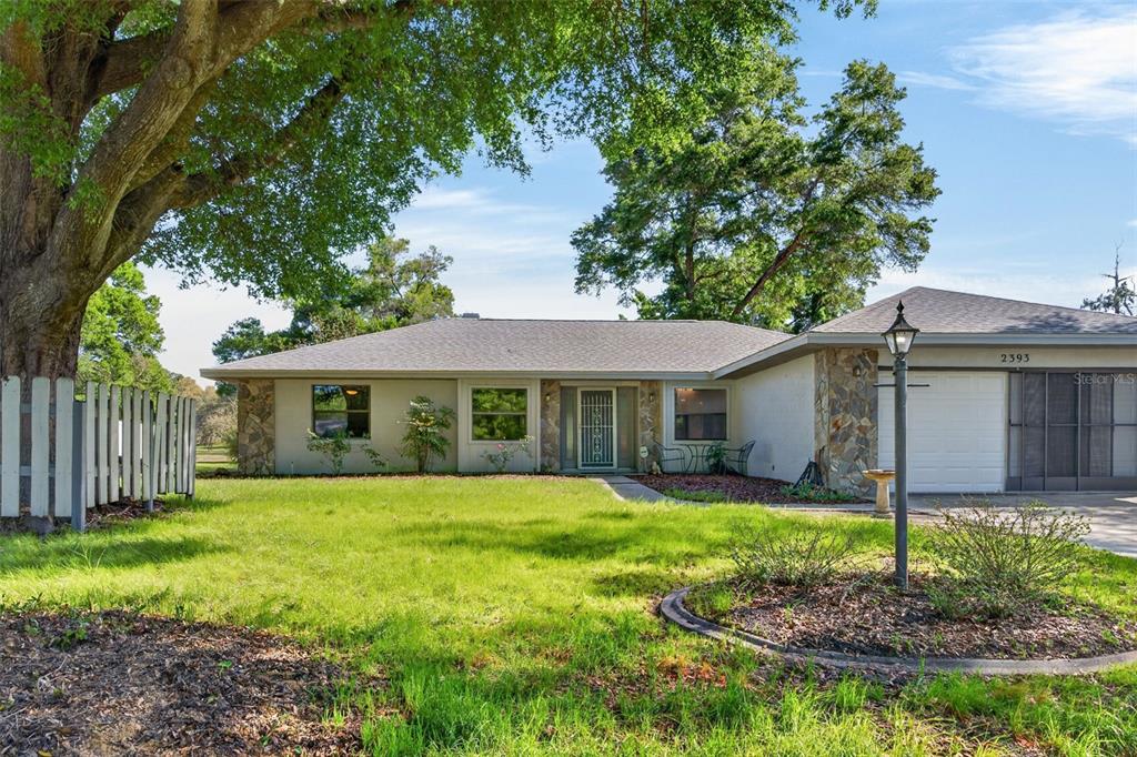 A single-story house with a stone facade, a large tree, and a front lawn — 2393 W FAIRWAY LOOP, CITRUS SPRINGS, FL