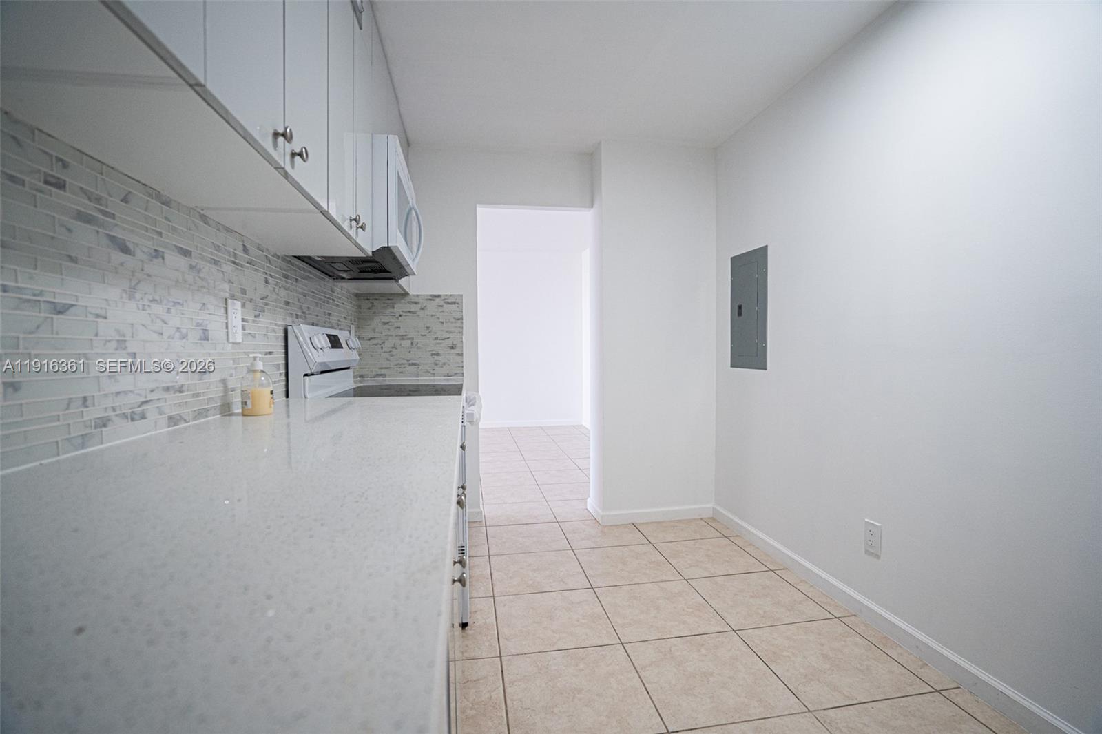 A galley-style kitchen features white cabinets, quartz countertops, and a light-colored tile floor — 1849 S Ocean Dr # 1509, Hallandale Beach FL 33009, HALLANDALE BEACH, FL