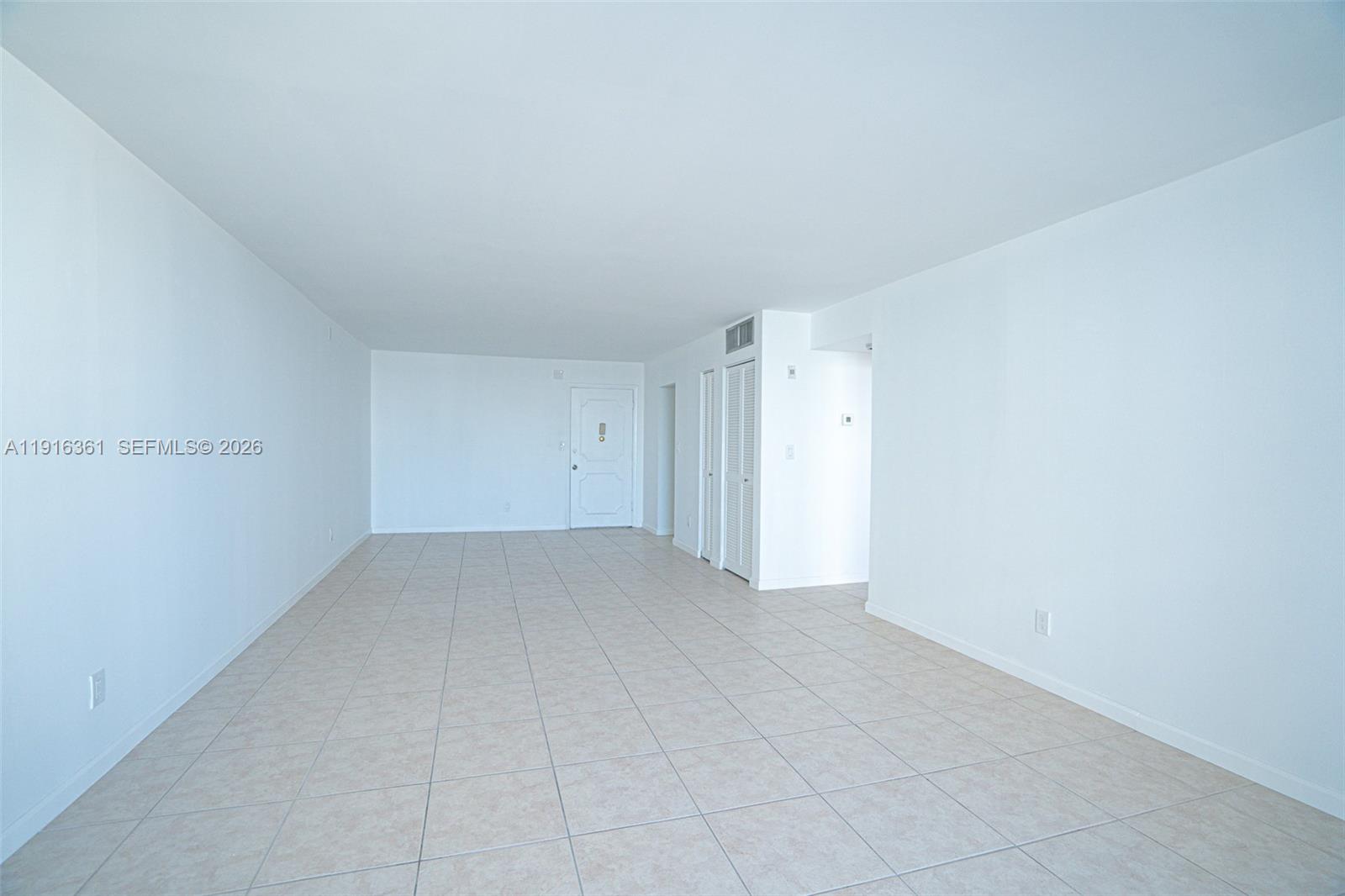 An empty room features white walls, light-colored tile flooring, and a sliding glass balcony door — 1849 S Ocean Dr # 1509, Hallandale Beach FL 33009, HALLANDALE BEACH, FL