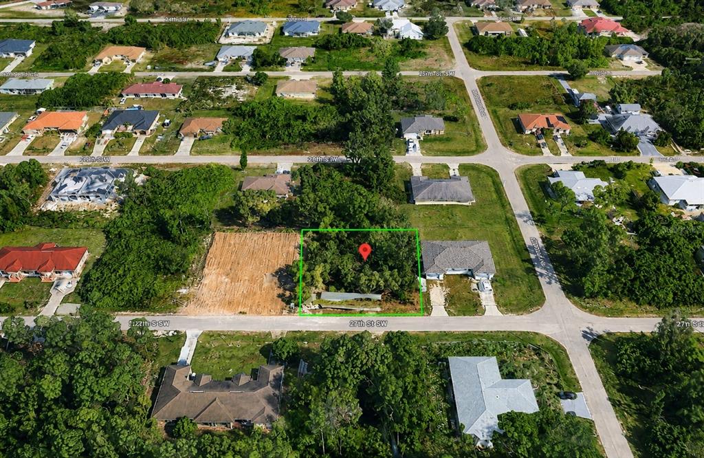 An aerial view shows a vacant, tree-covered residential lot marked with a red pin — 5204/5206 27TH ST SW, LEHIGH ACRES, FL