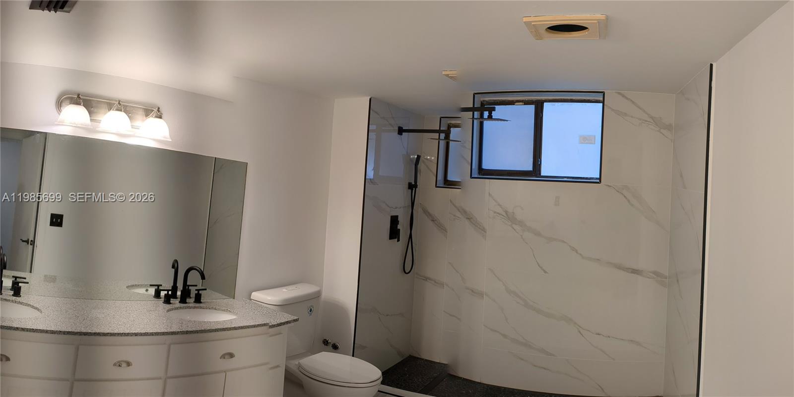 A bathroom features a white vanity, a toilet, and a walk-in shower with marble-look tile — 601 Ives Dairy Rd # 8, Miami FL 33179, MIAMI, FL