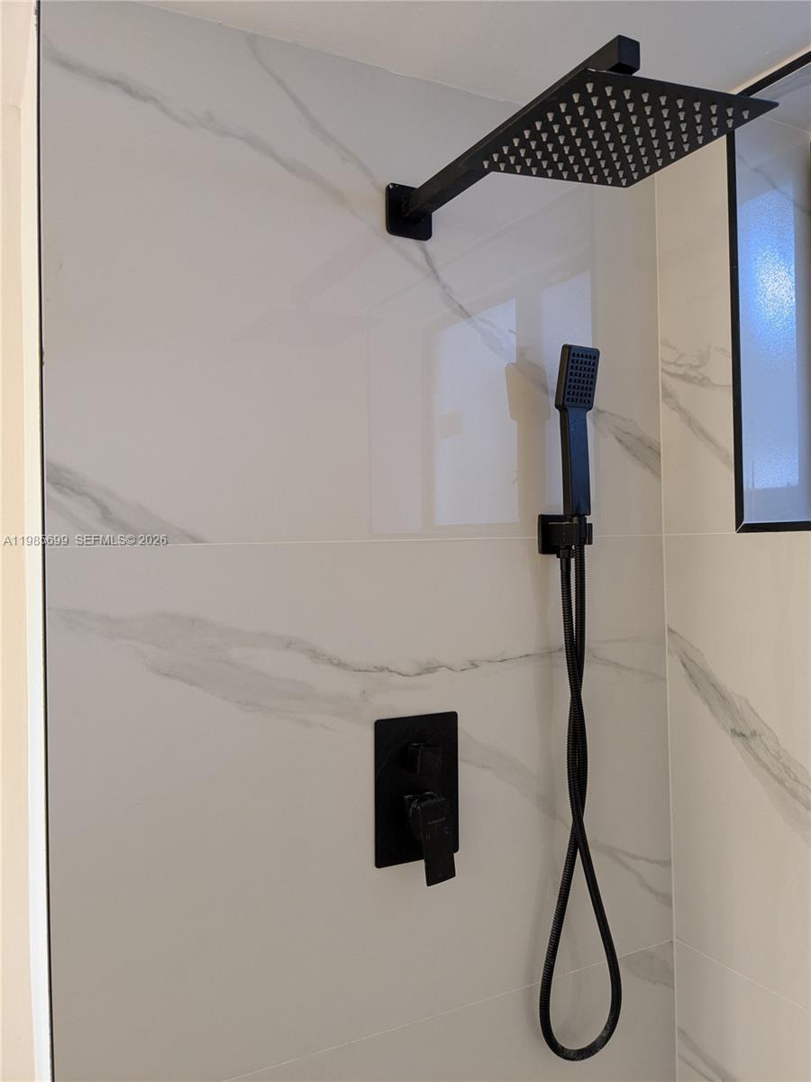 A modern shower features white marble-look tiles and matte black fixtures — 601 Ives Dairy Rd # 8, Miami FL 33179, MIAMI, FL
