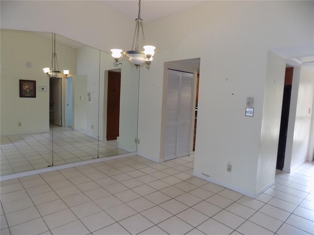 A dining area features white tile flooring, a mirrored wall, and a hanging chandelier — 9663 86TH AVENUE UNIT 9663, SEMINOLE, FL