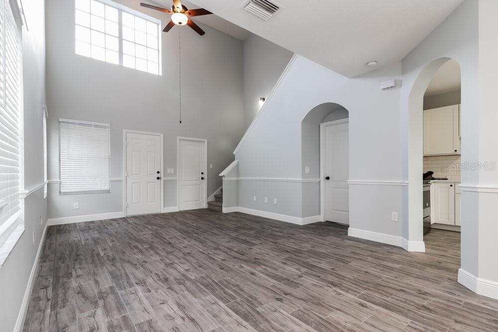 A living room with high ceilings, grey walls, wood-look flooring, and an arched entryway — 18034 BIRDWATER DRIVE, TAMPA, FL