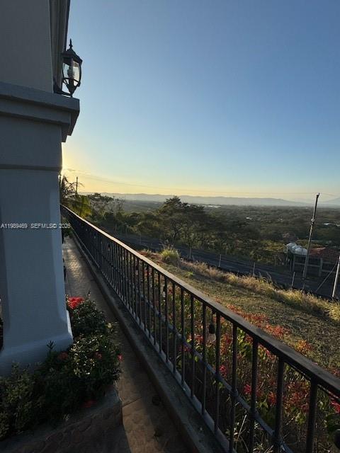 A balcony with a black metal railing overlooks a scenic landscape at sunset — KM 9.5 Carretera Vieja A. Leon, NI Man, NI