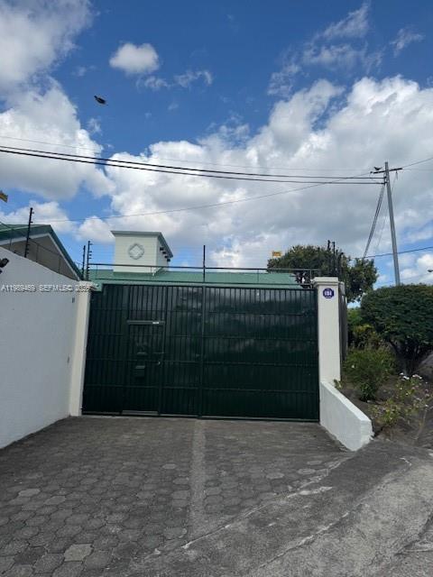 A dark green metal gate secures the entrance to a property with a paved driveway — KM 9.5 Carretera Vieja A. Leon, NI Man, NI